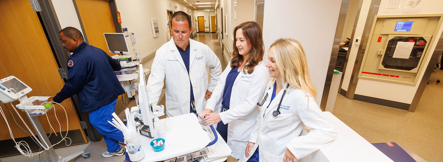 Three hospitalists interact while charting a patient encounter.